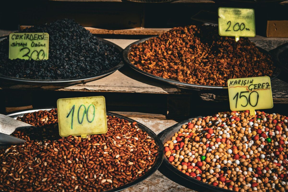 Colorful display of dried fruits and nuts in market with price tags, ideal for culinary and travel themes — kalonji price in pakistan