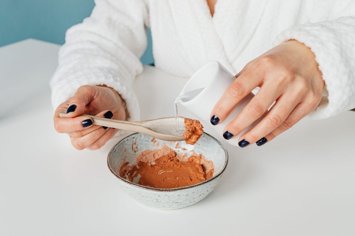 Close-up of a person mixing a natural clay mask with water for skincare — Shilajit honey syrup for skin benefits