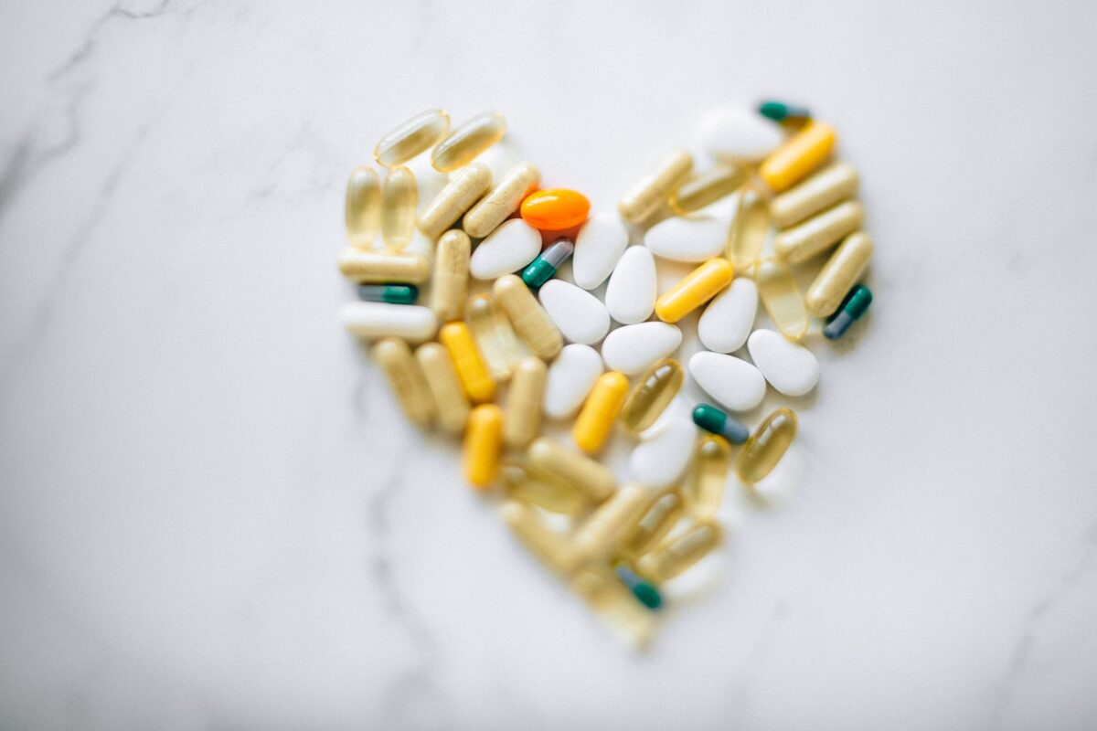 Colorful pills arranged in heart shape on a marble surface, symbolizing health and wellness, related to Shilajit honey syrup heart health benefits